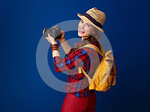 Smiling young woman hiker with modern DSLR camera taking photo