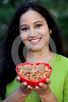 Smiling young woman hodling bowl of almonds