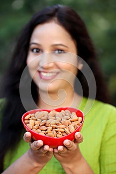 Smiling young woman hodling bowl of almonds