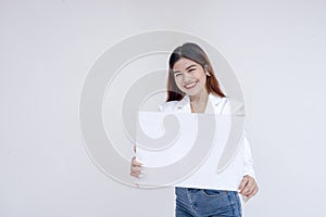 A smiling young woman holding blank sign to her front while looking at the camera. Isolated on a white background