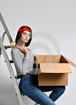 Smiling young woman holding cardboard box  on white background