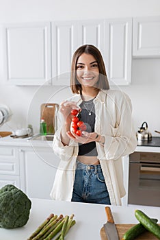 Smiling young woman holding cherry tomatoes