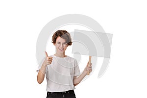 Smiling young woman holding empty signboard with copy space and showing thumb up photo