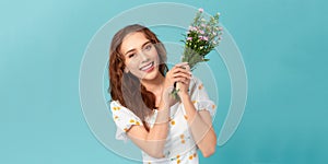 Smiling young woman holding a european michaelmas daisy bouquet on blue background. The concept of beauty and romance