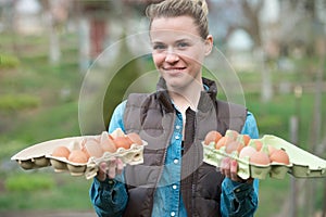 Smiling young woman holding Fresh chicken eggs in hands outdoors