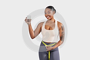 Smiling Young Woman Holding Glass of Water and Measuring Tape