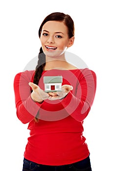 Smiling young woman holding house model