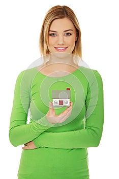 Smiling young woman holding house model