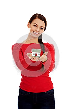 Smiling young woman holding house model