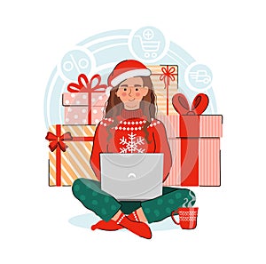 Smiling young woman holding a laptop with gifts on background. Girl wearing a scandinavian sweater and a Santa hat. Online