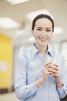 Smiling young woman holding mug, portrait