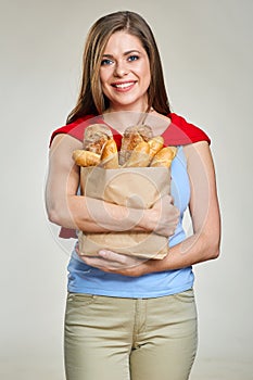 Smiling young woman holding paper bag with bread.