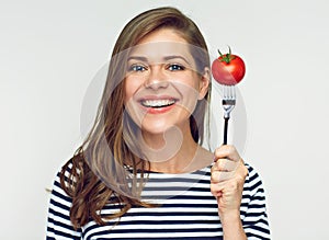 Smiling young woman holding tomato on fork.