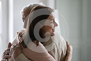 Smiling young woman hugging older man, enjoying tender moment