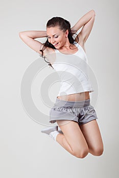 Smiling young woman jumping in air over white background