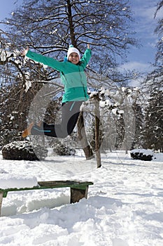 Smiling young woman jumping on a sunny winter day