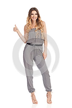 Smiling Young Woman In Jumpsuit Is Showing Thumb Up