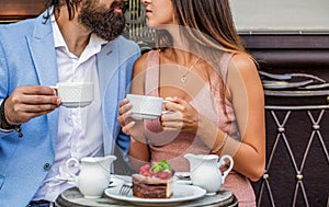 Smiling young woman kissing boyfriend while having coffee at cafe. Couple drinking coffee in restaurant. They drinking