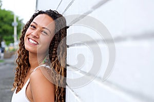 Smiling young woman leaning against a wall