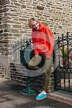 smiling young woman leaning at fence and looking away on cozy street mont saint