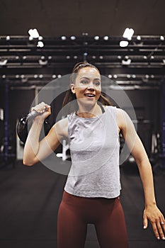 Smiling young woman lifting a dumbbell at the gym