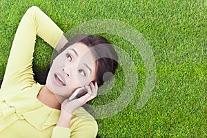 Smiling young woman listening with cell phone on grassland