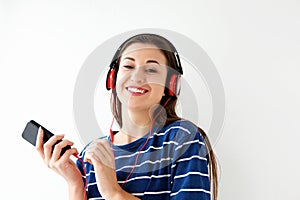 Smiling young woman listening to music with smart phone and headphones