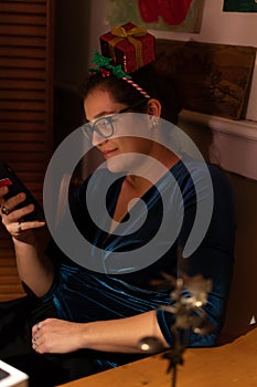 Smiling young woman looking into her cellphone at christmas