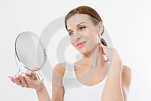 Smiling young woman looking in mirror isolated on white background. Skin care and anti aging concept. Beauty and body health.