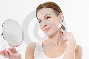 Smiling young woman looking in mirror isolated on white background. Skin care and anti aging wrinkle concept. Beauty and body