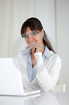 Smiling young woman looking at you using laptop