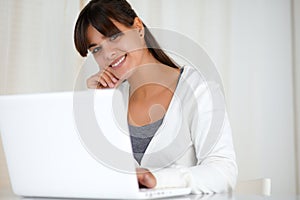 Smiling young woman looking at you using laptop