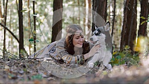 Smiling young woman lying in the forest and having a moment of tenderness with her darling pet