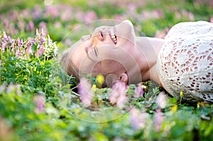 Smiling young woman lying in grass and flowers