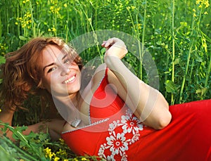 Smiling young woman lying in green grass