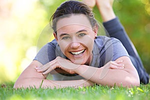 Smiling young woman lying outdoors on grass