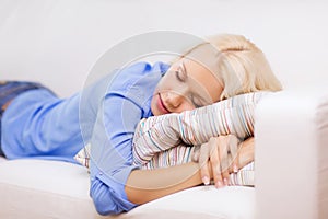 Smiling young woman lying on sofa at home