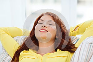 Smiling young woman lying on sofa at home