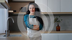 Smiling young woman maid housewife mistress baker housekeeper with long curly hair wearing checkered apron standing with