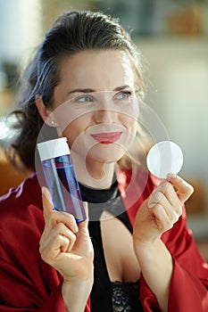 Smiling young woman with makeup remover and cotton pads