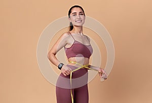 Smiling Young Woman Measuring Waist And Looking At Camera