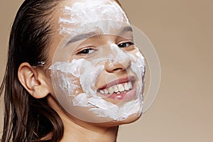 Smiling young woman with moisturizer on the cheeks in the eye area Youth and Skin Care Concept