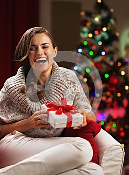 Smiling young woman near christmas tree with present box