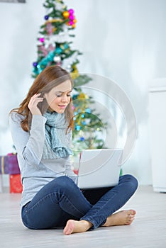 smiling young woman near christmas tree using laptop