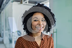 Smiling young woman in office setting with natural curls