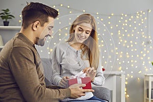 Smiling young woman opening box with birthday or Valentine present from her boyfriend