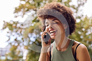 Smiling Young Woman Outdoors Laughing As She Talks On Mobile Phone