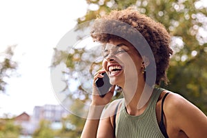 Smiling Young Woman Outdoors Laughing As She Talks On Mobile Phone