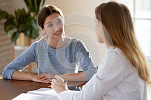 Smiling young woman patient listening to doctor at meeting