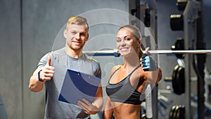 Smiling young woman with personal trainer in gym